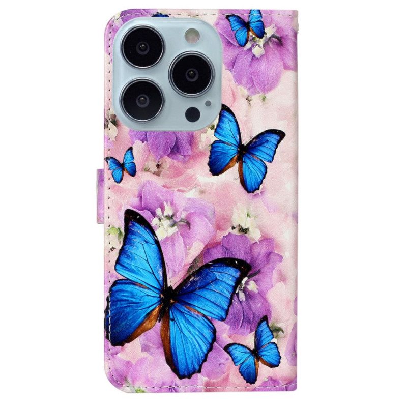 Folio-hoesje iPhone 16 Pro Telefoonhoesje Blauwe Vlinders En Paarse Bloemen Met Riempje